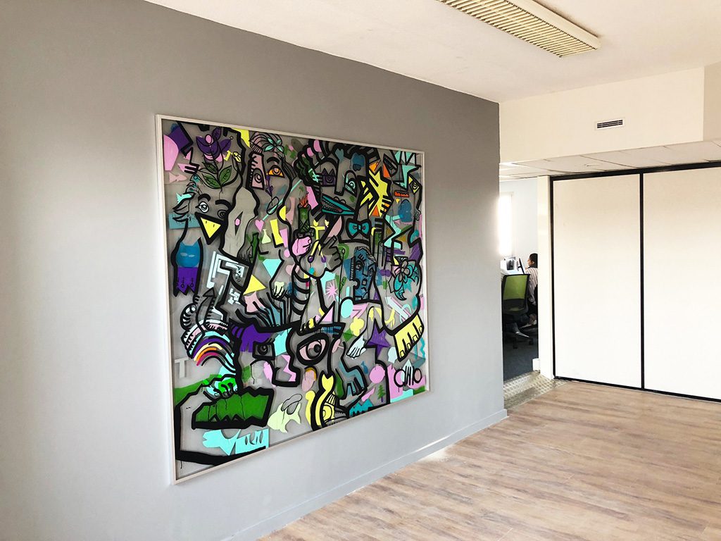 un tableau géant coloré et en plexi transparent, encadré dans une entreprise sur un mur gris