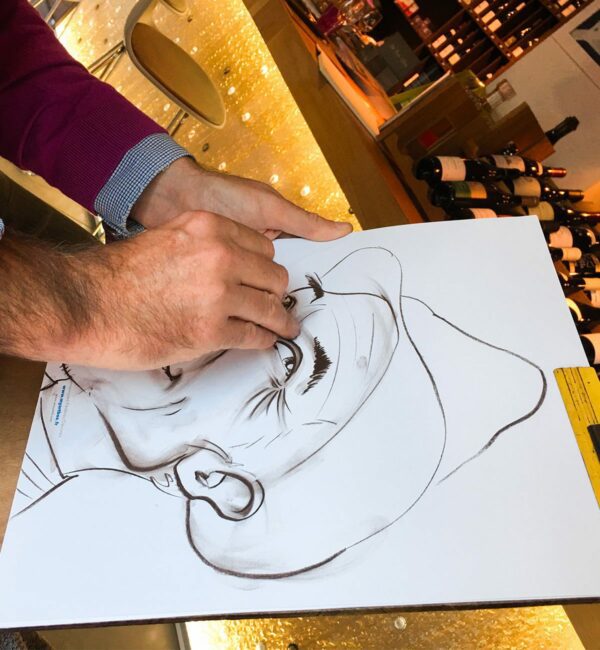Gros plan sur un dessin caricature noir et blanc format A3 avec les mains du caricaturiste Christophe Chazot en train de dessiner à Lyon en animation Close up