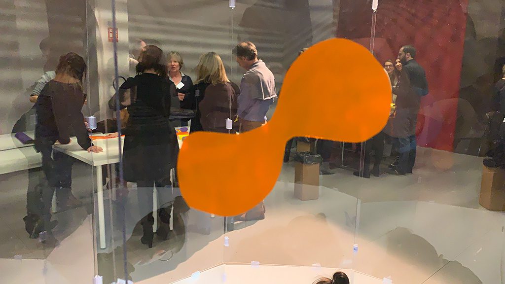 une forme simple orange découpée dans du vinyle collé sur le tube plexi transparent lors d'un atelier team building pour intéroger et surprendre à la manière de rené magritte