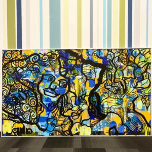 28 Idées cadeau art contemporain - Une Œuvre d'art colorée exposée devant un mur décoré de bandes de couleurs réalisée lors d'une animation Fresque Géante Totem Box XL à Rouen