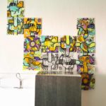 Une fresque évolutive happiness management composée de plaques de plexi décorées de vinyle de couleurs et assemblées librement autour d'un meuble dans une petite entreprise aux murs blancs