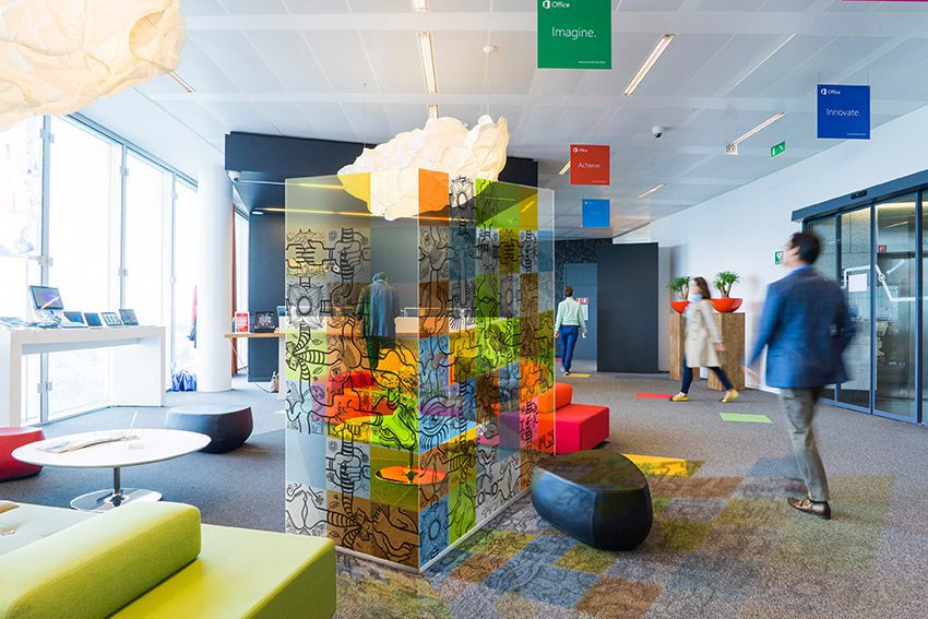 Paroi de protection plexiglass - La séparation qui crée du lien. 4 une paroi vitrée décorée de carrés colorés fresque open space installée au milieu d'un hall commun dans une entreprise