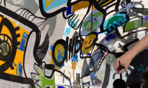 Team Building de Luxe aNa artiste Dans son tube plexi art qui devient une fresque géante une fois dépliée
