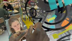 Un geste inclusif lors d'une animation intégration originale fresque collective plexiglass et stickers My Art Box à Rouen encadrée par l'animateur Christophe Chazot