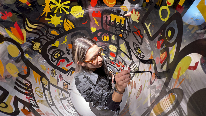 Animation fresque ana artiste en live painting dans son cylindre transparent lors d'un team building graffiti éco-responsable My Art Box à Paris