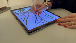 Une femme aux ongles rouges signe la fresque digitale livre d'or artistique en cours de création