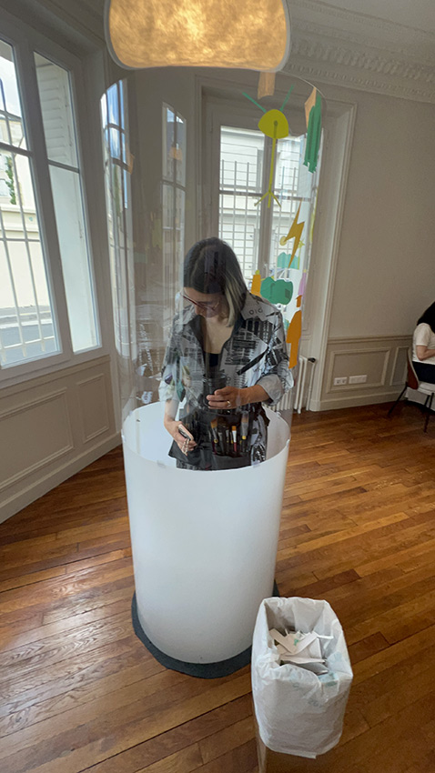 1 fresque Live en team building pour avocats à 50 à Paris 10 ana artiste accueille les participants et commence dans son tube plexi transparent en team-building pour avocats éco-responsables à Paris