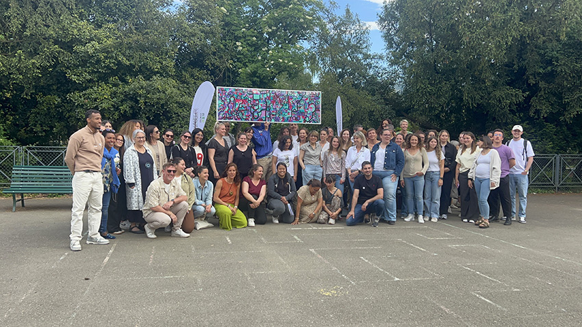 Le groupe des participants au team building secteur de la petite enfance à Genève animé par Christophe Chazot posent devant leur œuvre commune souvenir à la fin de l’atelier collaboratif de aNa artiste