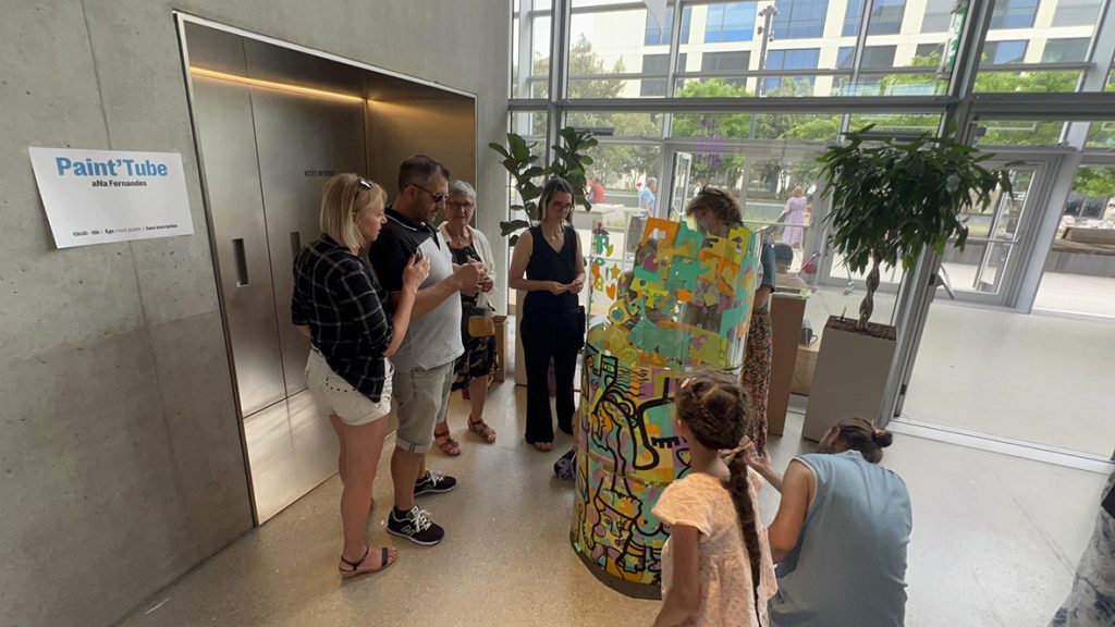 Des participants autour du cylindre en plexiglas de l'artiste aNa en animation fresque éco-responsable à Genève