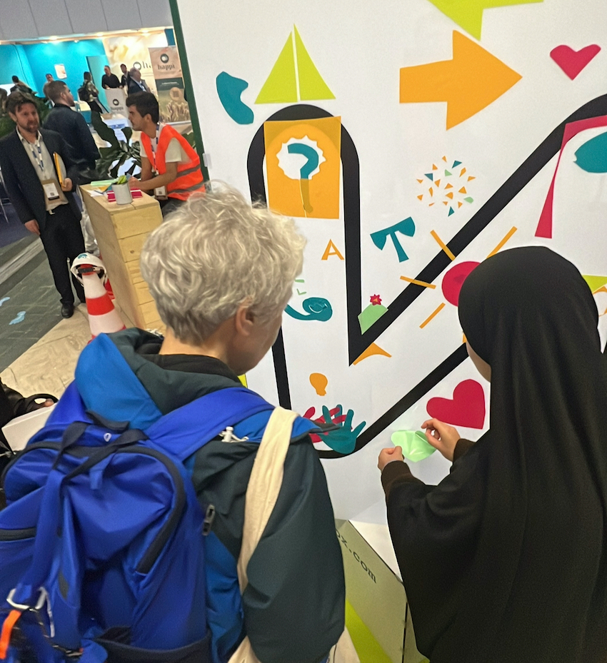 Des participantes qui ne se connaissent pas collaborent sur le stand de la fresque cube plexi en animation amélioration continue à Paris