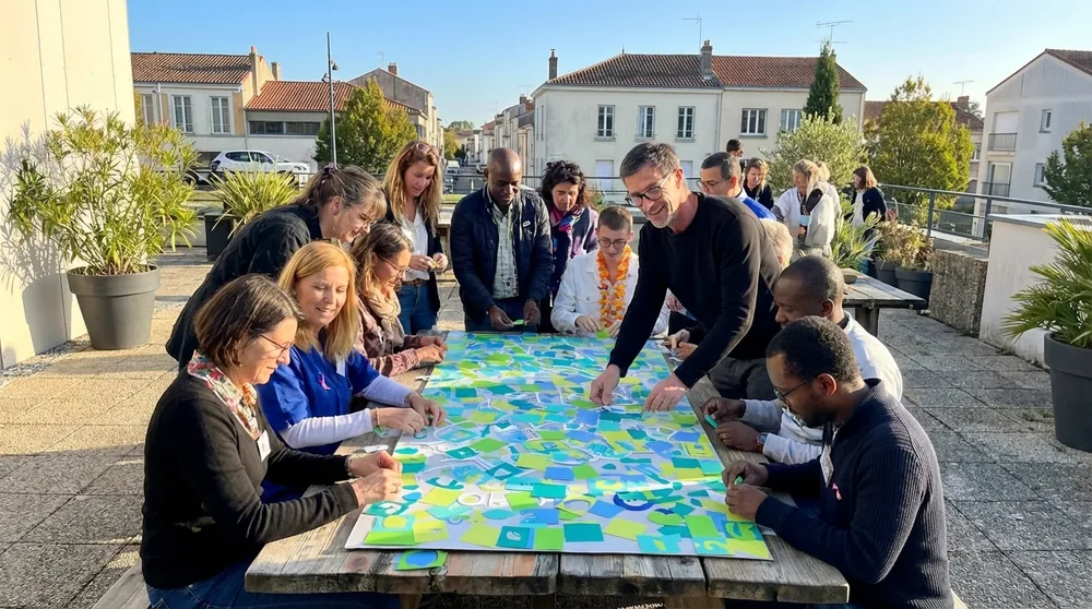 Vue de la fresque collaborative à la CPAM avec participants et le coach Christophe Chazot en tenue My Art Box. CPAM Deux-Sèvres et animation artistique inclus.