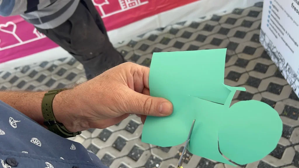 Participant découpant une forme en vinyle coloré pour fresque collaborative en inauguration