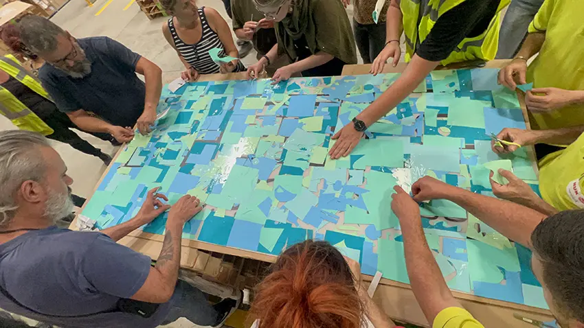 Collaborateurs réalisant une fresque collaborative en vinyle sur plexiglas lors d’un team building RSE industriel