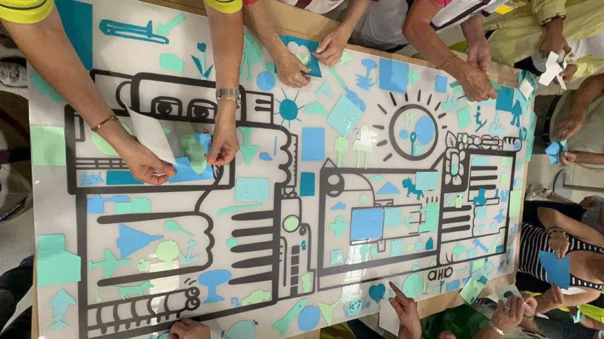 Participants collant des formes en vinyle sur une fresque plexiglas lors d’une animation RSE en milieu industriel