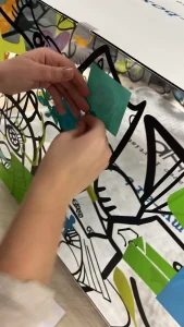 Participant collant des éléments colorés sur un cube artistique My Art Box pendant un team building en équipes