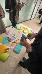 Équipe en atelier de team building artistique My Art Box manipulant des feuilles de papier colorées pour créer un cube collaboratif