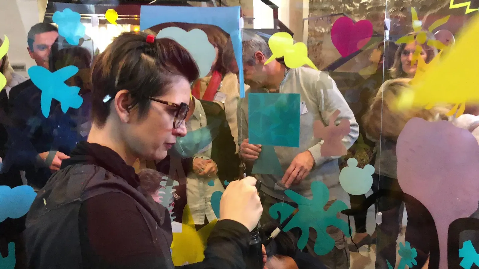 Artiste créant une fresque collective à Paris dans un tube transparent pour AXA.
