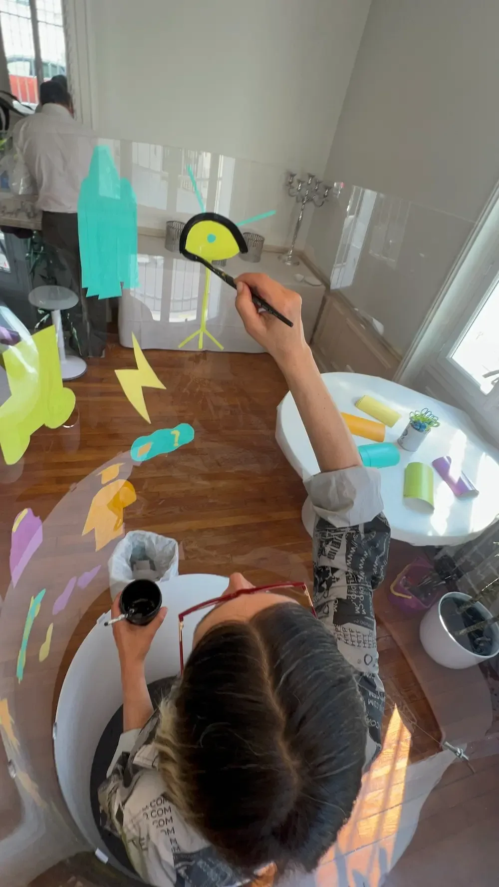 Personne créant une œuvre colorée sur vitre lors d'une animation écoresponsable à Paris.