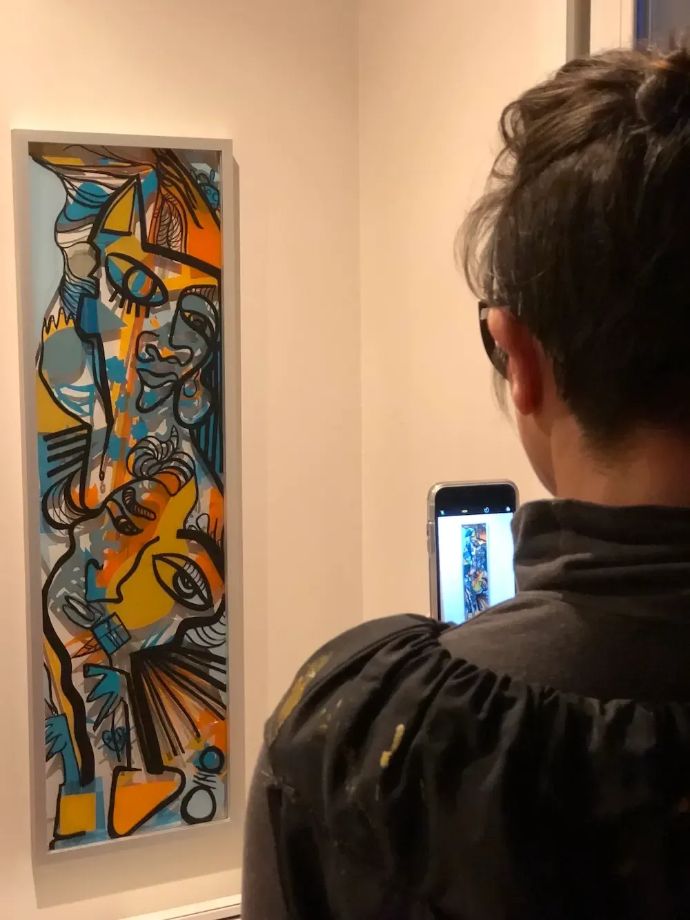 Une femme prenant en photo une œuvre colorée par aNa artiste My Art Box lors d'un anniversaire.