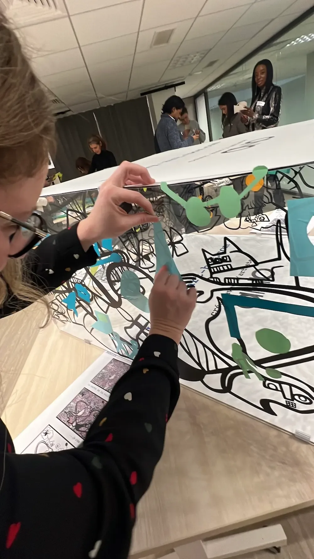 Personne créant un collage en vinyle sur plexiglas lors d'un team building à Paris avec Ogletree Deakins.