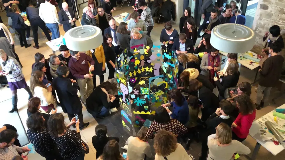 Scène d'un événement avec participants portant des EPI classiques tels que blouses et gants, illustrant l'éco-responsabilité avec My Art Box.