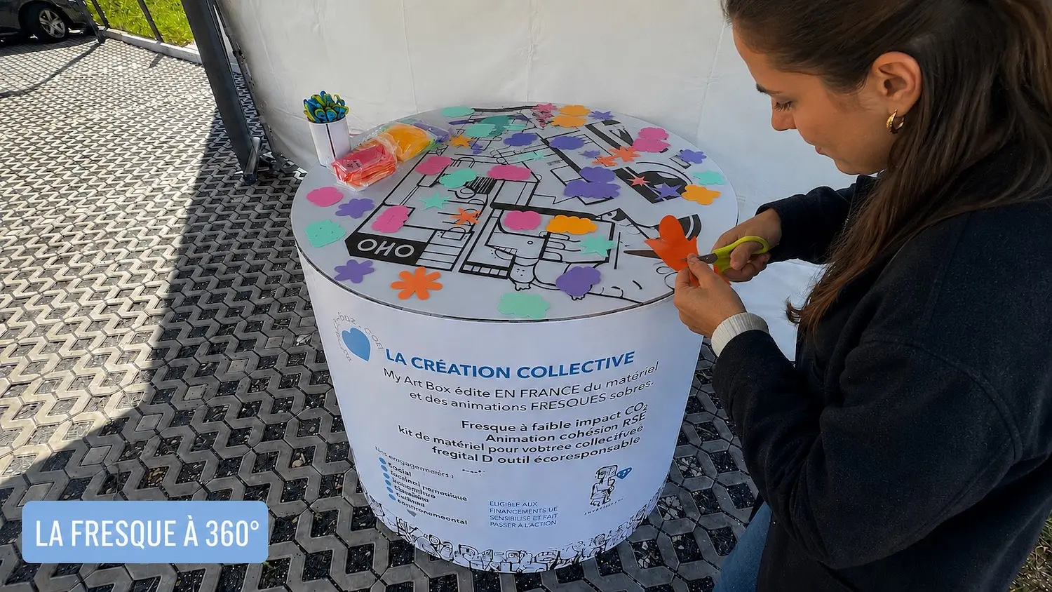 Participante découpant des formes adhésives colorées pour une Fresque à 360° de 900mm My Art Box lors d’une animation collaborative éco-responsable