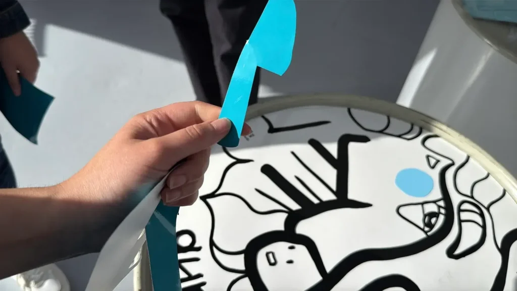 Main tenant une découpe bleue lors d'un événement My Art Box avec aNa artiste.