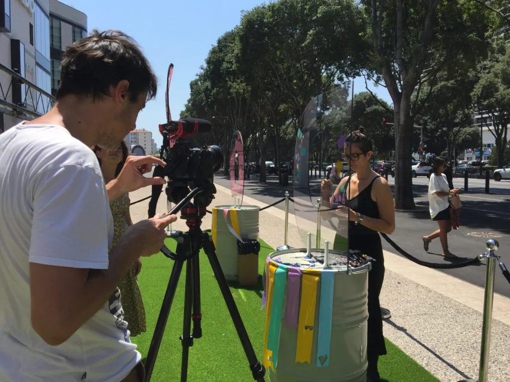 Une équipe de tournage filme les interactions sociales des participants devant une fresque graffiti au centre commercial Prado.