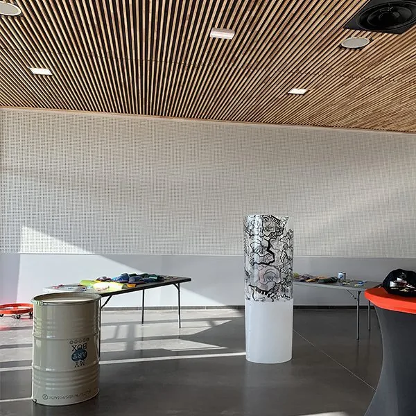 Participants personnalisant une grande colonne artistique transparente lors d'une cérémonie de pose de première pierre.
