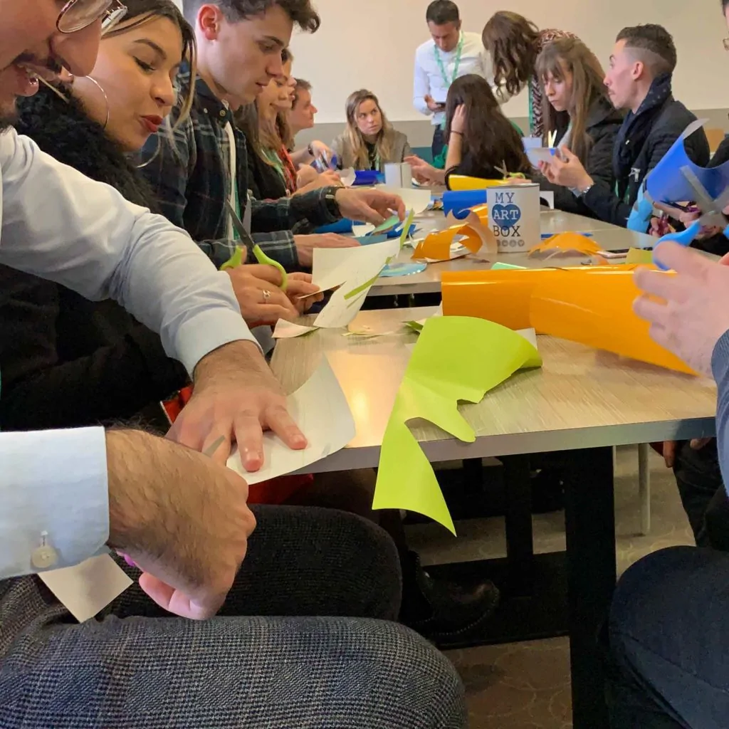 Groupe de collaborateurs assis autour d'une grande table lors d'un atelier créatif de cohésion à Rouen.