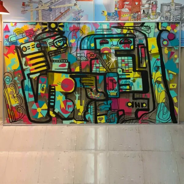 Une œuvre encadrée en aluminium Idée Animation Fresque sur plexi. Formes colorées collées sur une plaque géante de plexi transparent et réhaussées par le dessin original de l'artiste aNa à l'encre noir.