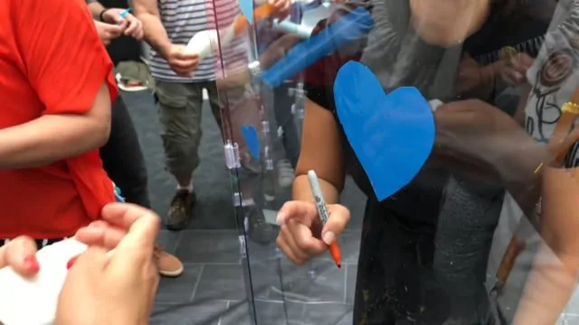 Participants engagés dans la création d'une fresque collaborative colorée lors d'un atelier de management ludique.