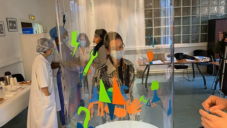 Participants s'activant autour d'une œuvre collaborative colorée pour les 50 ans de l'Hôpital Antoine Béclère.