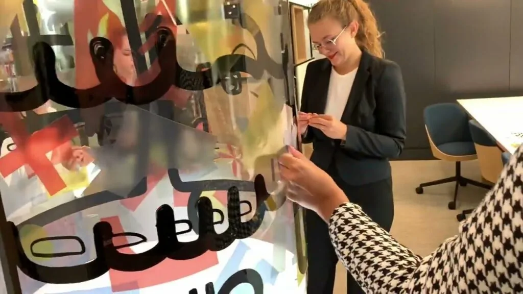 Participants assemblant une fresque collaborative sur un totem en plexiglas lors d'un événement à Mérignac.