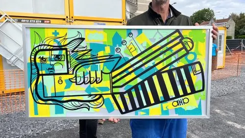 Une œuvre d'art grand format encadrée représentant un plan architectural coloré lors d'une inauguration de bâtiment.