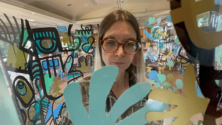 Des participants s'activent autour d'une fresque collaborative transparente créée par aNa artiste lors d'un séminaire.