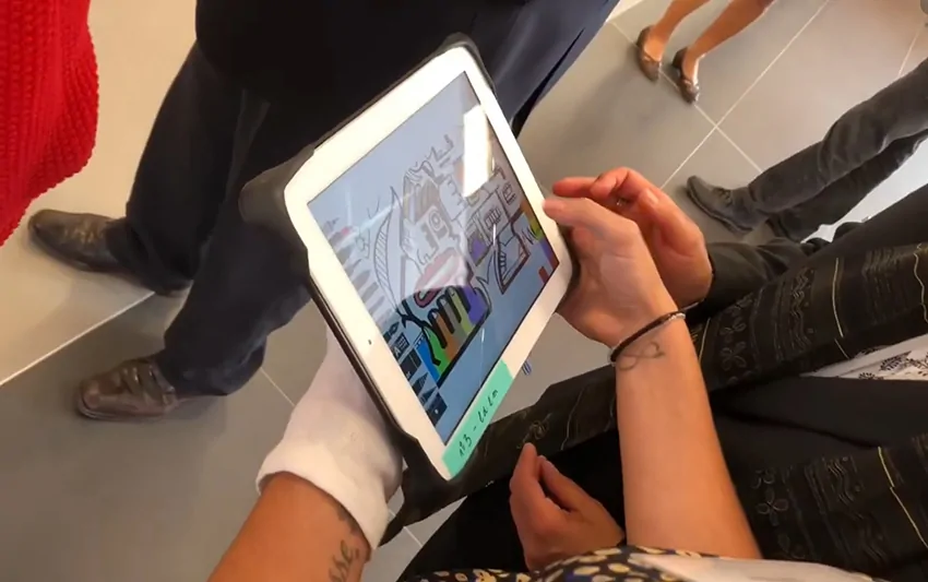 Participants utilisant des tablettes tactiles pour créer une œuvre numérique collective lors d'un événement à Saint-Étienne.