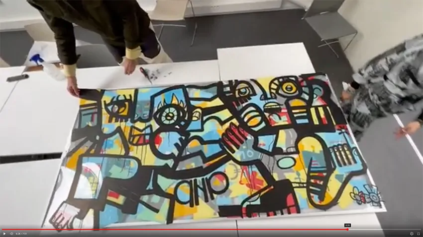 Mains d'animateurs installant un cadre élégant sur une fresque colorée réalisée par des collaborateurs.