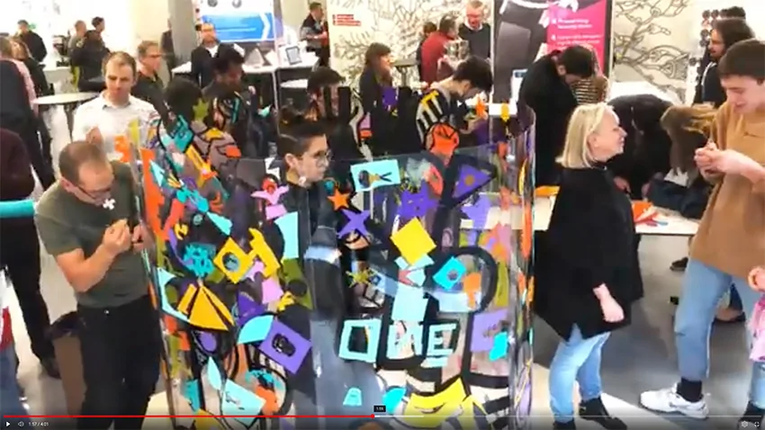 Participants engagés dans la création d'une fresque collective colorée lors d'un événement à Neuchâtel.