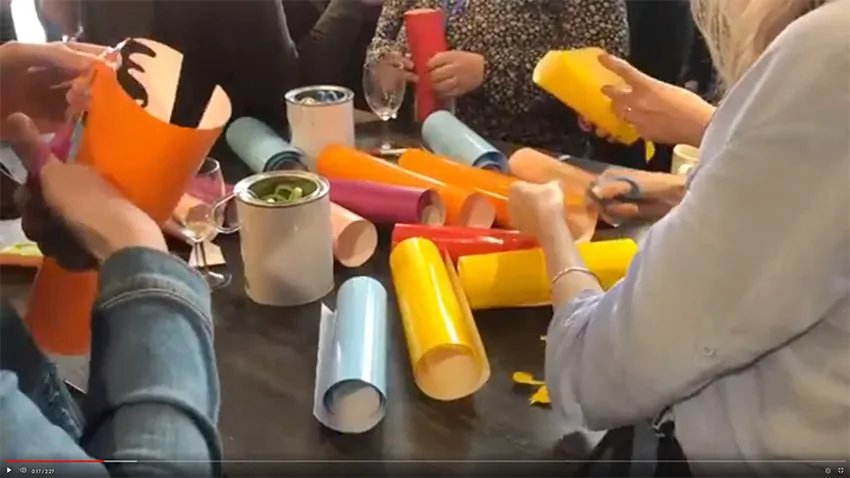 Ciseaux, rouleaux de vinyle coloré et cartons de réemploi disposés sur une table pour un atelier créatif.