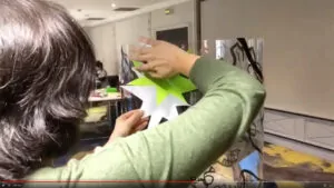 Une participante à l'animation team building Grenoble colle son vinyle coloré découpé sur la toile en plexiglass