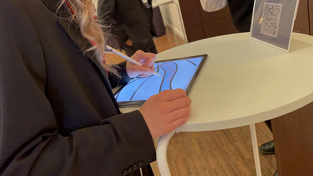 Une jeune femme signe la fresque digitale livre d'or artistique en cours de création projetée sur écran