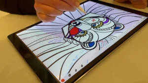 Une jeune femme signe la fresque digitale livre d'or artistique en cours de création et projetée sur un écran en même temps pour être suivie des autres invités