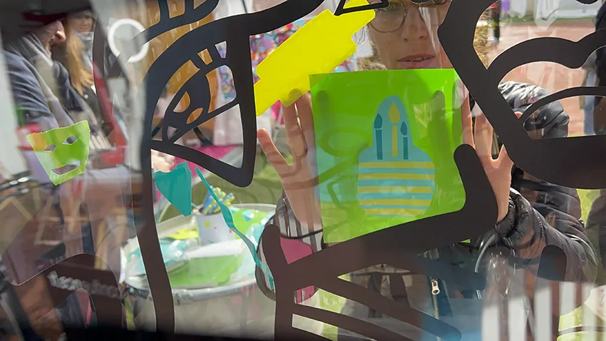 Une idée de gâteau d'anniversaire avec trois bougies découpé dans du vinyle vert jaune et bleu par une participante avec les ciseaux de réemploi lors d'une animation de stand inclusive écoresponsable à Lyon en extérieur animée par my art box et posée sur le plexi