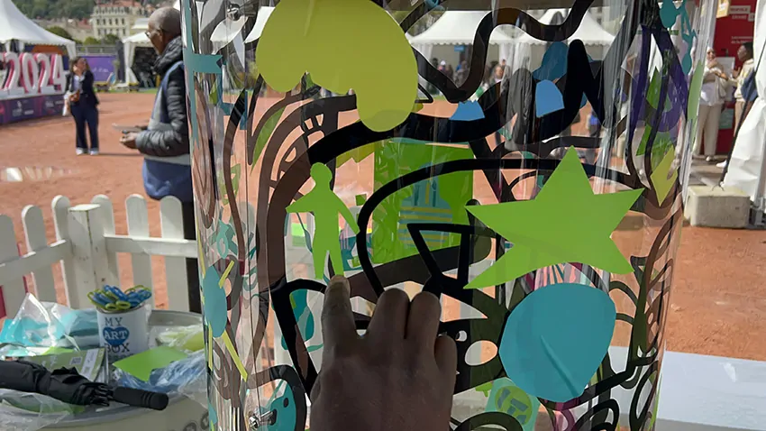 Une idée de personnage découpé dans du vinyle vert par un participant avec les ciseaux de réemploi lors d'une animation de stand inclusive écoresponsable à Lyon en extérieur animée par my art box et posée sur le plexi