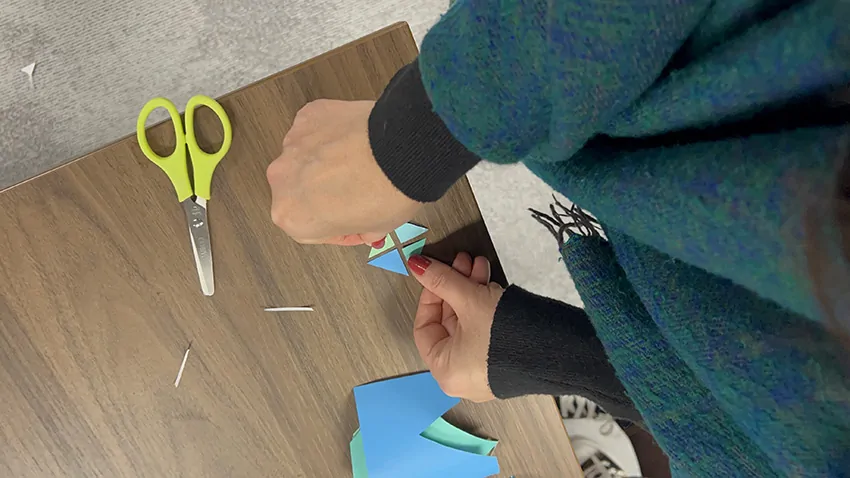 Une participante à la fresque de la frugalité My Art Box assemble un découpage sur la table devant elle