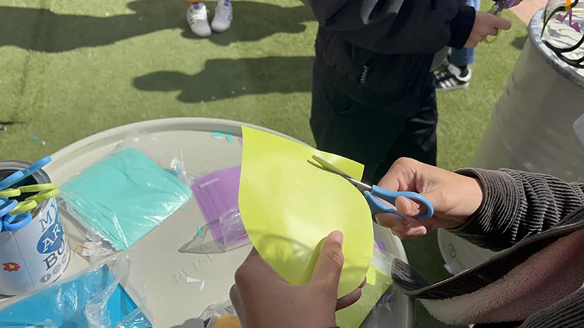 Une participante découpe une forme dans le vinyle vert claire avec des ciseaux de réemploi pour une oeuvre collective sans peinture Totem plexi My-art-box rse écoresponsable