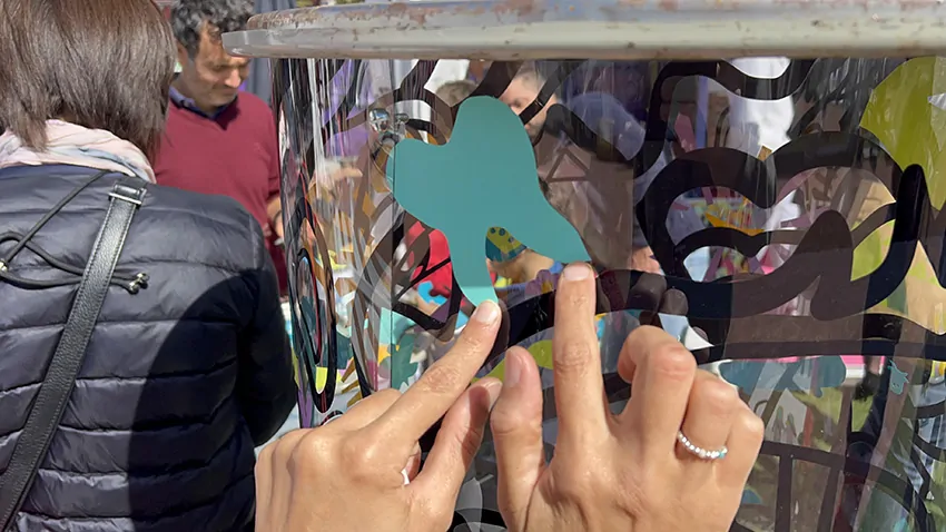 Une participante colle son idée découpée une forme de dent dans le vinyle vert avec des ciseaux de réemploi pour une oeuvre collective sans peinture Totem plexi My-art-box rse écoresponsable