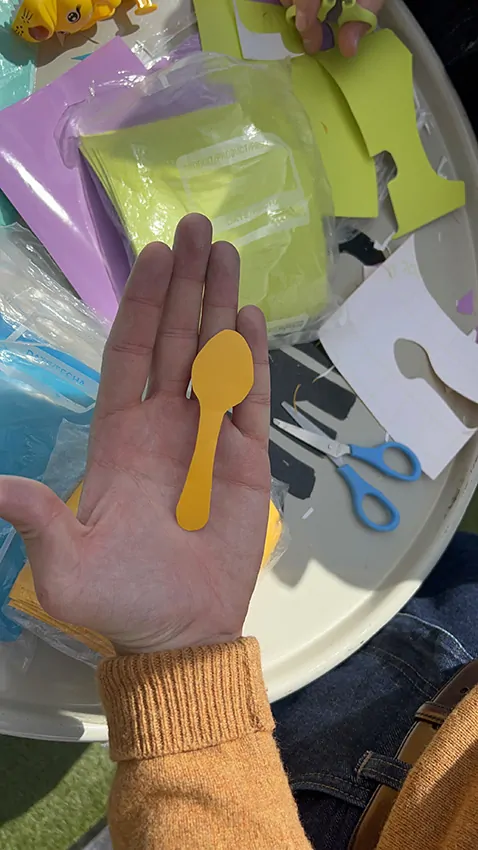 Une participante découpe son idée de petite cuillère orange pour une oeuvre collective sans peinture Totem plexi My-art-box rse écoresponsable