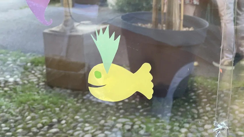 Un symbole de baleine jaune découpé dans des adhésifs et collé par un participant sur le plexi de la fresque en garden party à Genève en Suisse